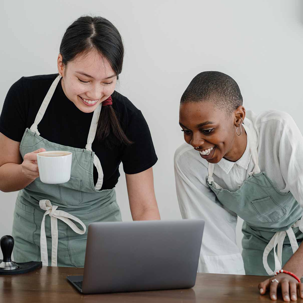 Niches Two women in aprons smiling at laptop