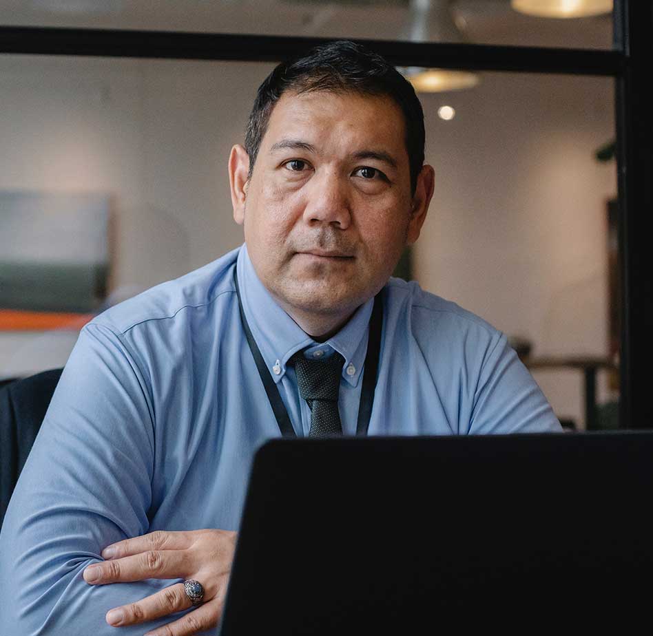 ac-testimonial-1 man in dress shirt and tie on laptop staring into the camera