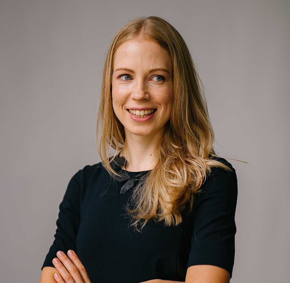 ac-testimonial-2 woman in business casual attire with arms crossed smiling looking off into the distance