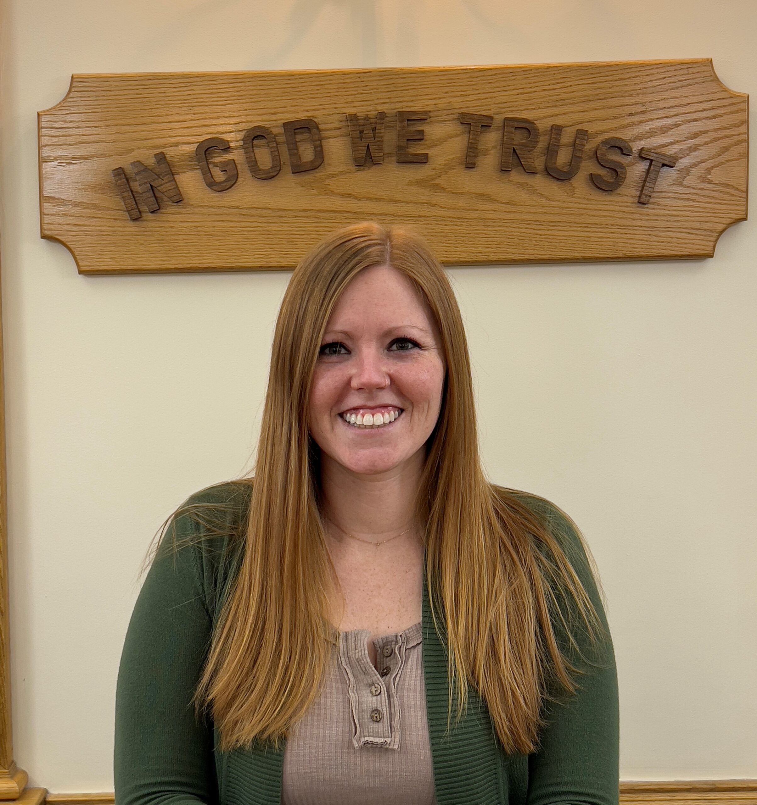 Portrait of Stephanie with In god we trust sign